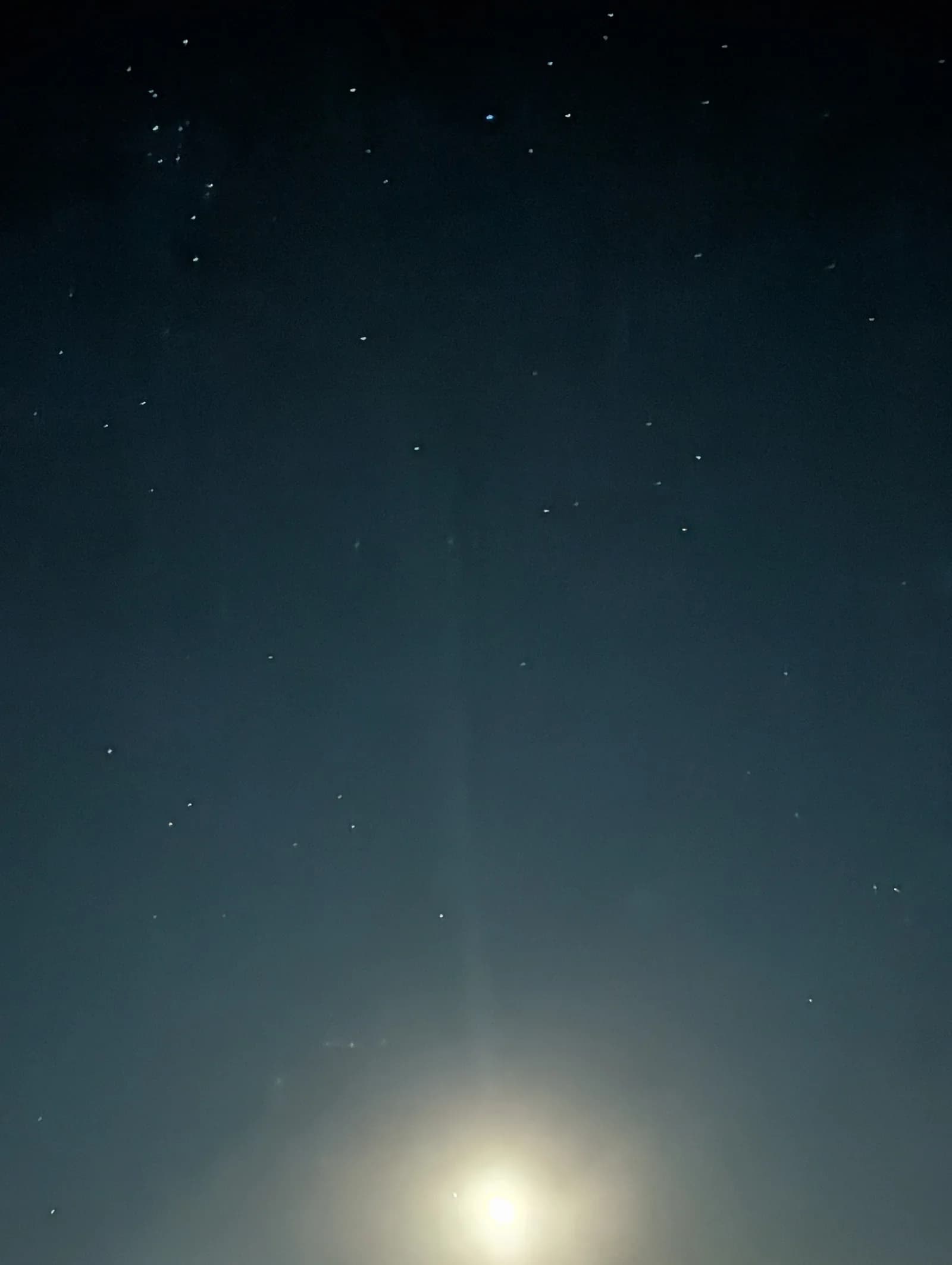 The moon glowing low in a dark desert sky scattered with stars.